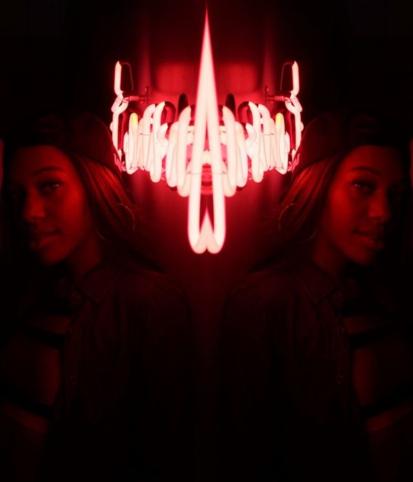 Woman in a calming yoga pose in a dark room with neon green light.